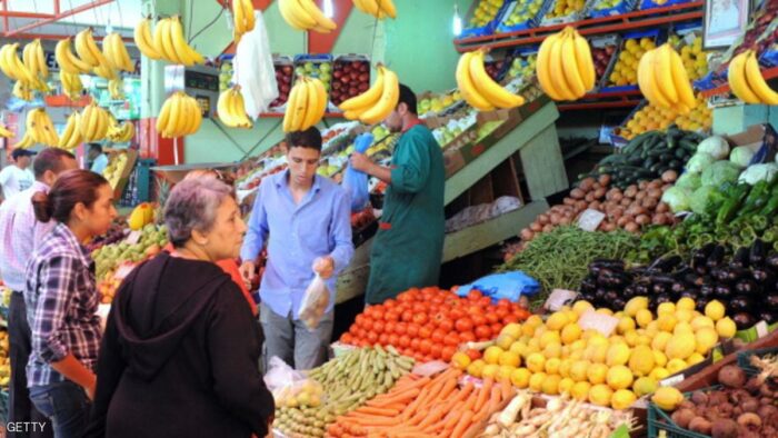 A fruit vendor serves customers at a mar